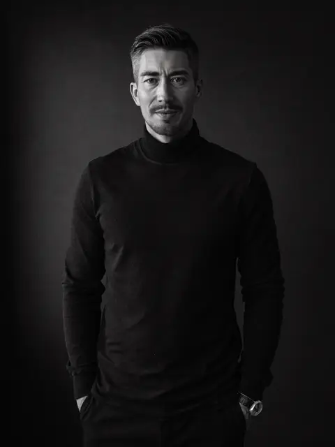 Jérémy Prost, pull col roulé noir, mains dans les poches